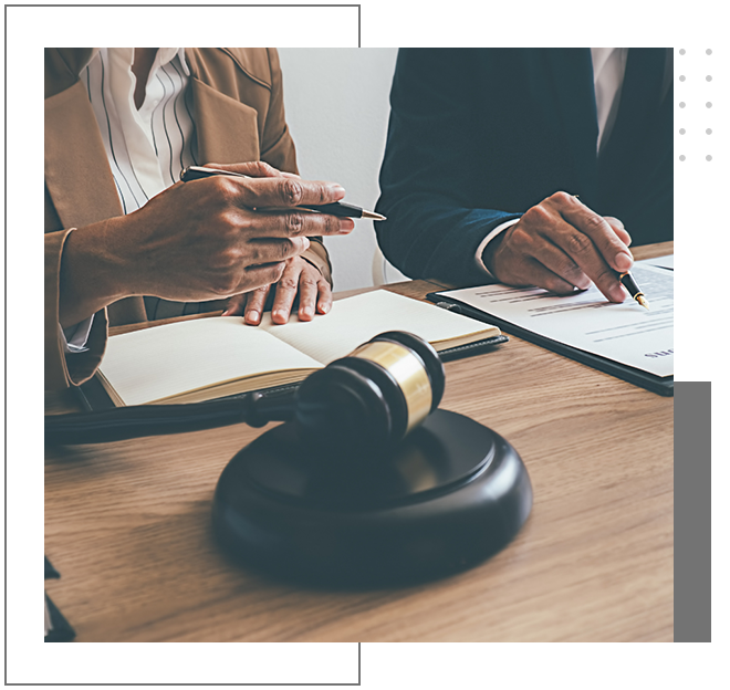 Two people sitting at a table with papers and a gavel.