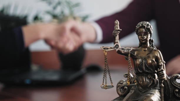 A person shaking hands over a statue of justice.